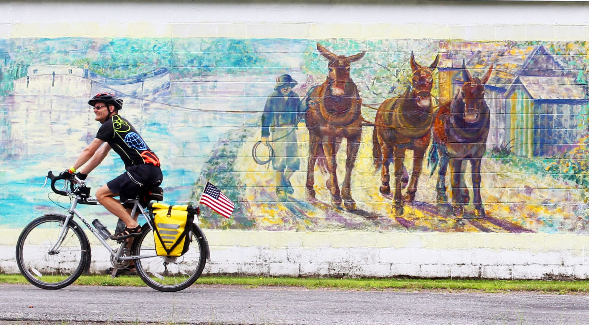 Empire State Trail photos: A colorful cyclist rides past a large painted mural along the Erie Canalway Trail, part of New York's new Empire State Trail.