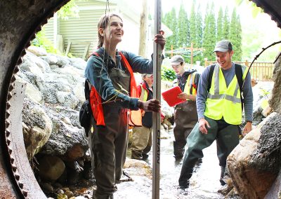 an environmental services field worker surveys and measures the height of a culvert