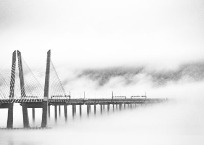 black and white picture of a large, modern bridge in the fog