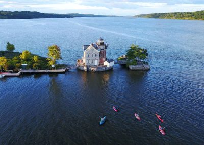 aerial view of lighthouse with blue water and colorful kayaks